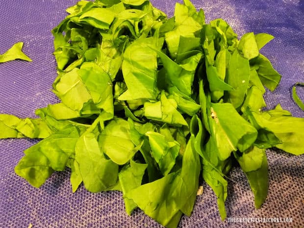 Fresh spinach is chopped into pieces before it is added to the pasta.