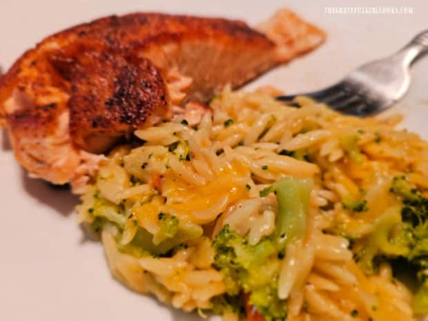 A piece of creole salmon is served next to the broccoli cheese orzo pasta.