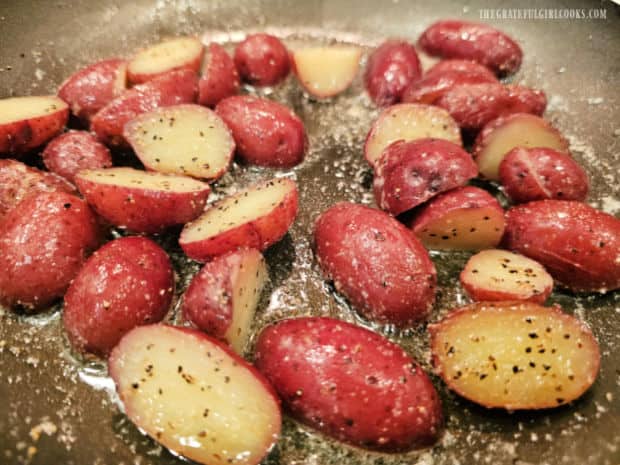 Buttery seasoned red potato halves are cooked in skillet until heated through.