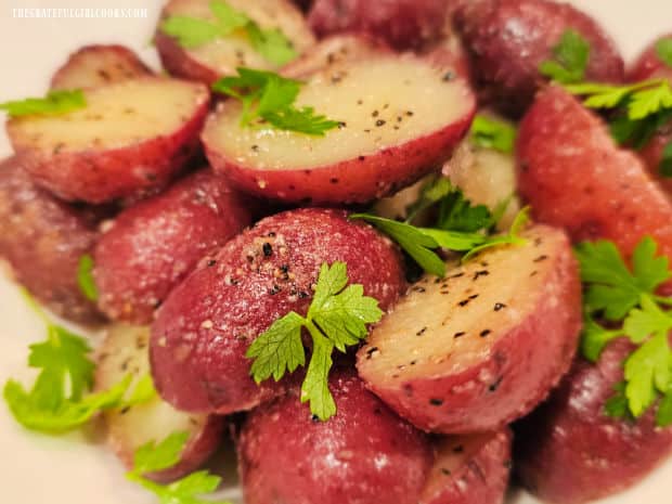 The garlic butter red potatoes are garnished for serving with fresh parsley leaves.