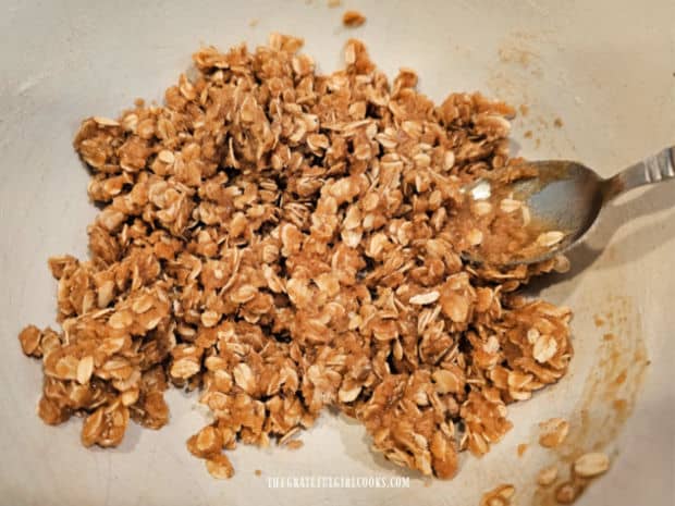 Oats. brown sugar, flour and spices are combined with melted butter in a bowl.