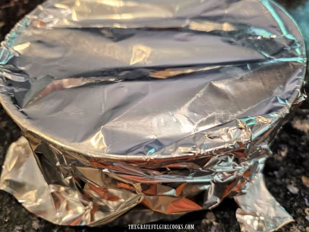 Aluminum foil is used to tightly cover the baking pan before cooking.