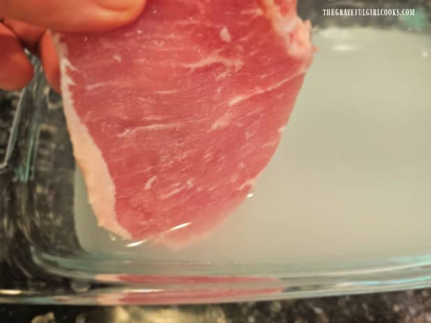A boneless pork chop is placed in a saltwater brine for 1-2 hours before cooking.
