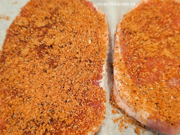 Both sides of the thick pork chops are covered with the spice mixture.