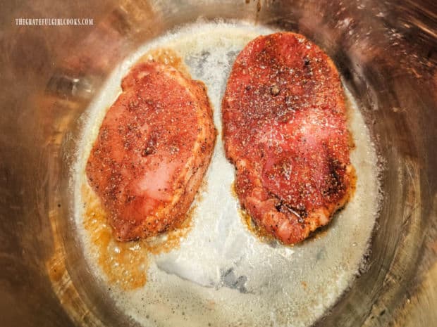 Pork chops are sautéed in melted butter in the Instant Pot.