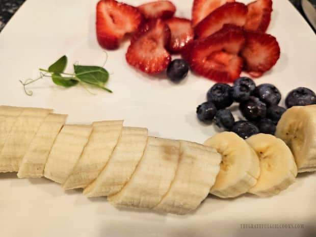 Strawberry and banana slices plus blueberries are used to garnish the waffles.