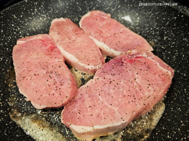 Seasoned pork chops are lightly browned in melted butter in a skillet.