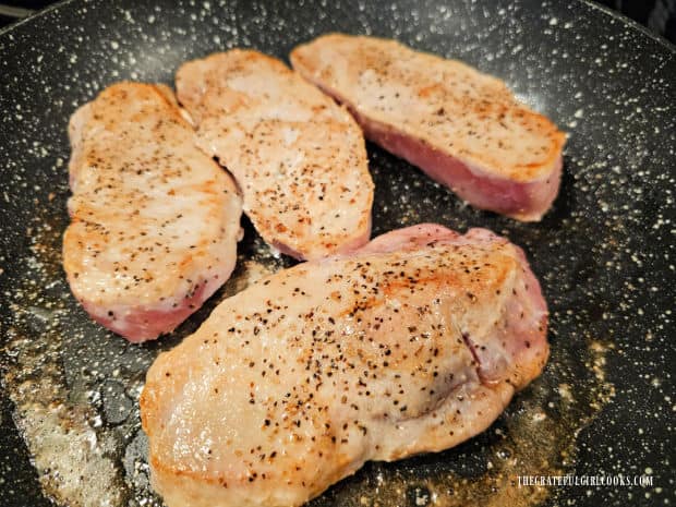 The pork chops are lightly browned on both sides but not fully cooked through.