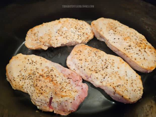 The pork chops are placed in a crockpot in a single layer.