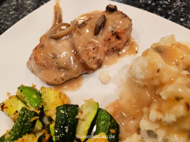 Gravy from crockpot is added to the pork chops and mashed potatoes on the plate.