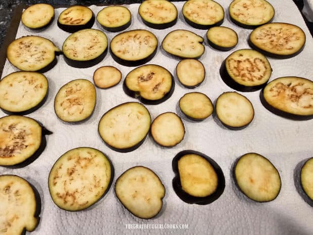 Two eggplants are sliced, then laid on paper towels and lightly salted.