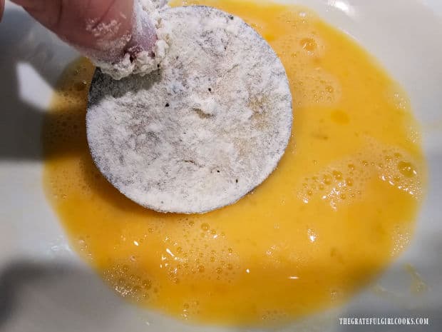 Flour-covered eggplant slices are then dipped in beaten egg mixture.