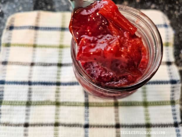 A close up of a spoonful of one jar strawberry rhubarb jam, ready to be eaten.