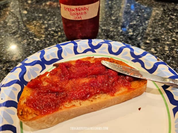 A piece of sourdough toast, covered with the strawberry rhubarb jam.
