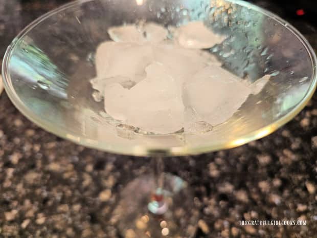 A cocktail glass is filled with ice cubes before adding liquid.