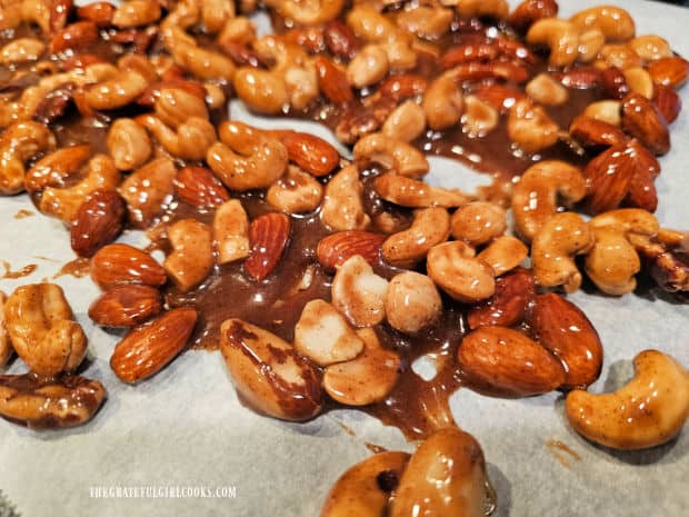 Pumpkin Spice Candied Nuts are spread in a single layer on parchment paper to dry.