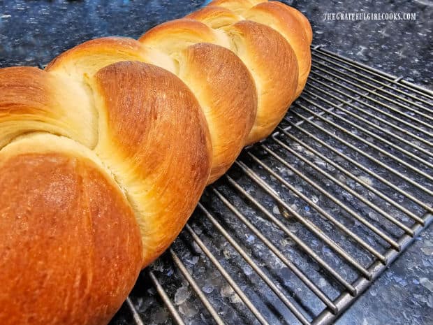 Beautifully browned, the challah loaf cools on a wire rack after baking.