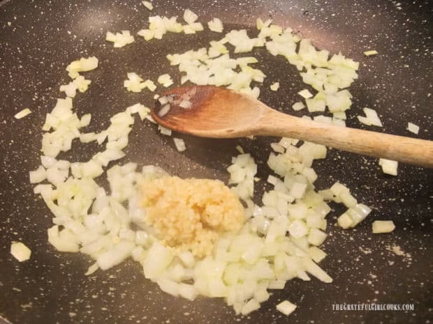 Minced garlic is added to cooked, chopped onion in a large skillet.