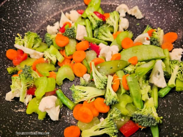 The chopped veggies are stir-fried in hot oil in a large skillet.