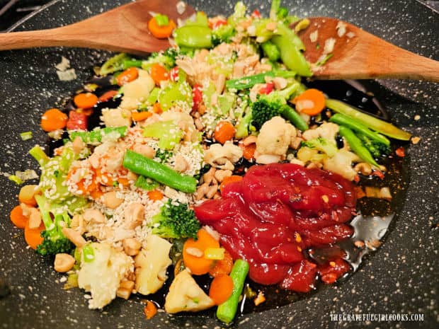 Sesame seeds and other ingredients for an Asian sauce are added to the skillet.