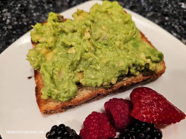 The mashed avocado is spread generously on the multi-grain toast.