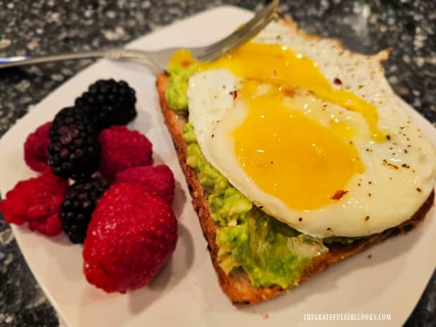 A plate filled with fresh berries and avocado toast and egg, ready to be enjoyed.
