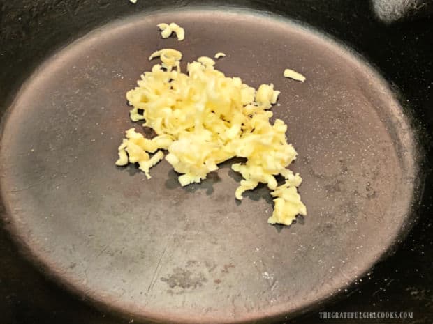 More grated butter is put in a cast iron skillet and skillet is pre-heated in oven.