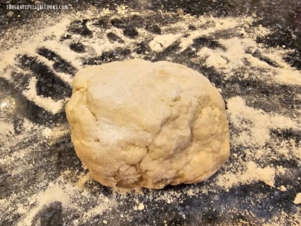 Dough is shaped into a ball and placed on a floured work surface.