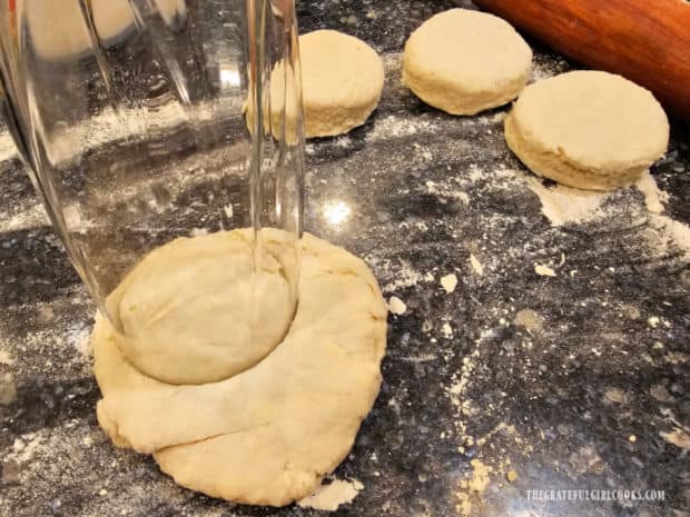 A glass is used to cut out the dough into 5 round biscuit shapes.