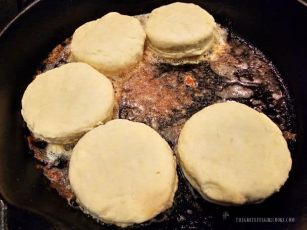 Biscuits are placed in the browned butter mixture in the preheated skillet.