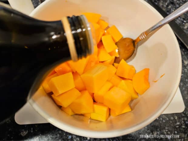 Oven-Roasted Butternut Squash - The Grateful Girl Cooks! Olive oil is poured over the squash cubes, then tossed to combine.