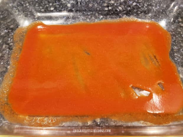 Air Fryer Cheese Enchiladas - The Grateful Girl Cooks! A small amount of enchilada sauce is spread on the bottom of the baking dish.