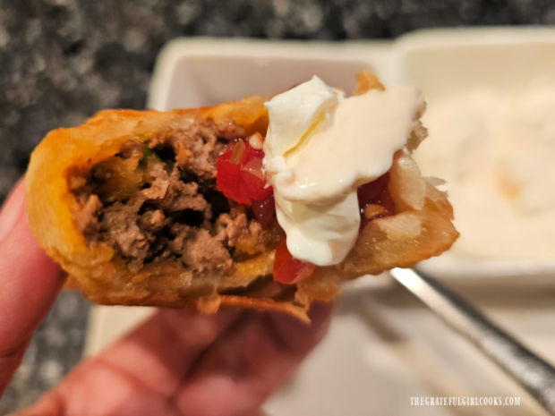 An inside peek at one of the ground beef empanadas with salsa and sour cream on it.