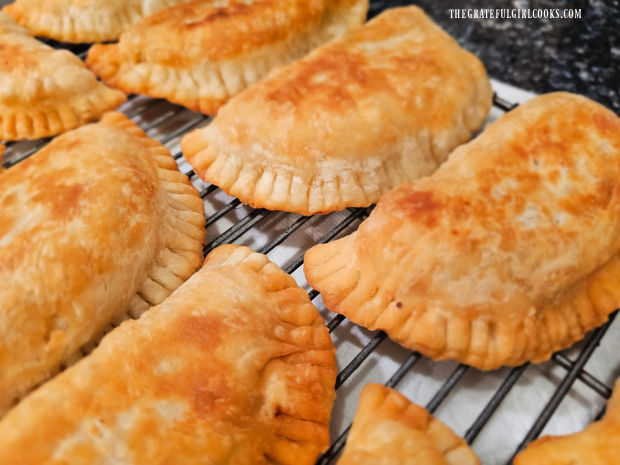 Close up of a few of the golden-brown beef empanadas on a wire rack cooling.