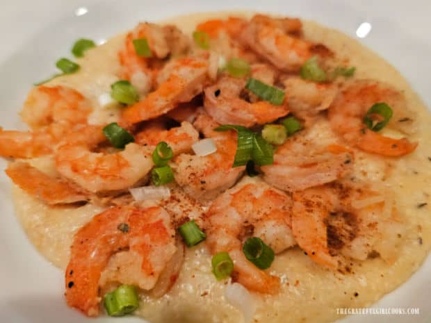 Cajun Shrimp and Cheese Grits are garnished with chopped green onions for serving.