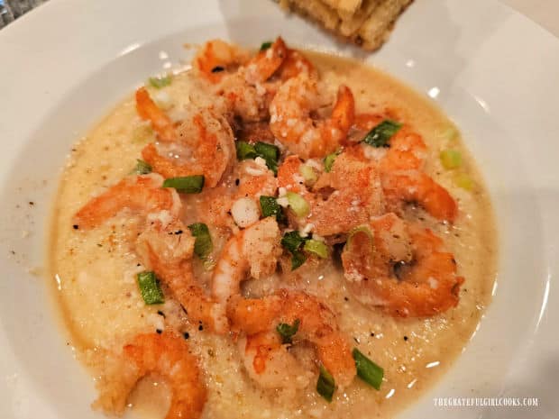 Sauce is spooned over the Cajun Shrimp and Cheese Grits then it is served.