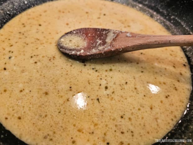 A sauce is made in a skillet and will be spooned over the cooked shrimp and grits.