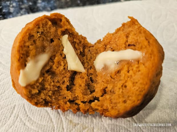 A pumpkin muffin cut in half, topped with softened butter.