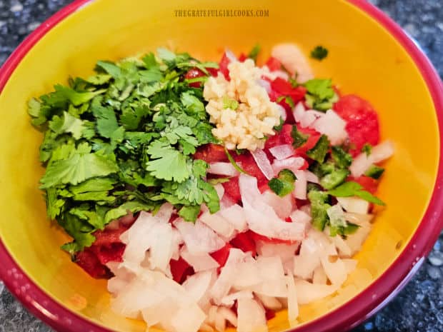 Onions, cilantro, garlic, lime juice and jalapeños are added to the chopped tomatoes.