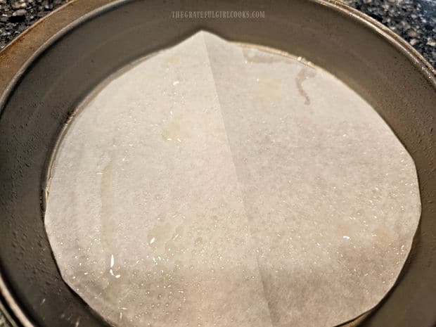 Parchment paper is put in the bottom of a greased 8" cake pan.