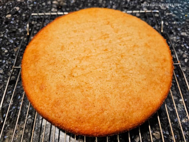 Lemon olive oil cake is flipped over so it is right side up on a wire rack.