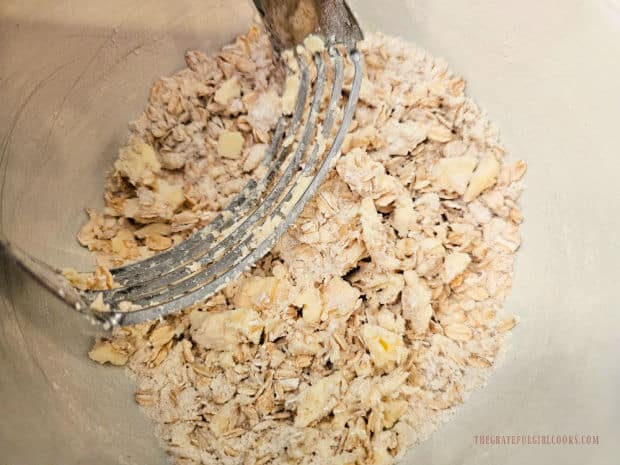 Using a handheld pastry blender to cut the butter into the topping.