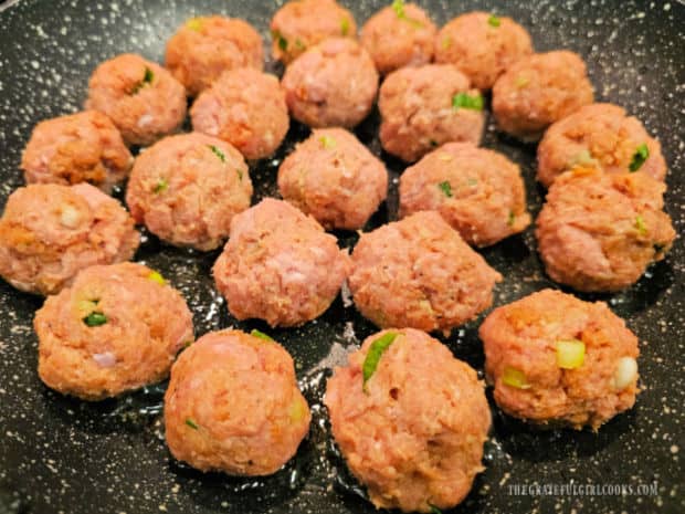 The meatballs are placed in hot oil in a single layer in a large skillet. 