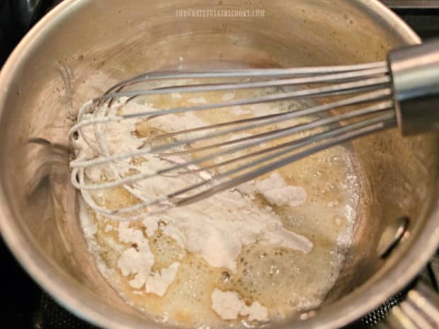 Flour is whisked into the melted butter forming a thick paste.