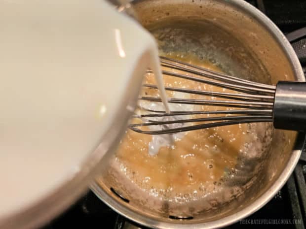 Milk is added and combined with the roux mixture in the pan.