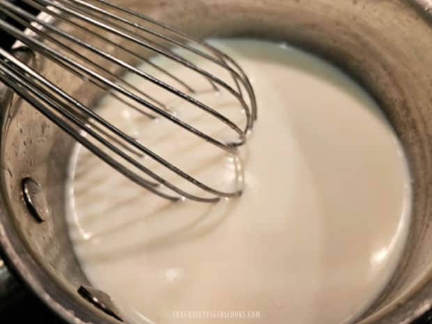 Whisking the milk, butter and flour mixture until it thickens.