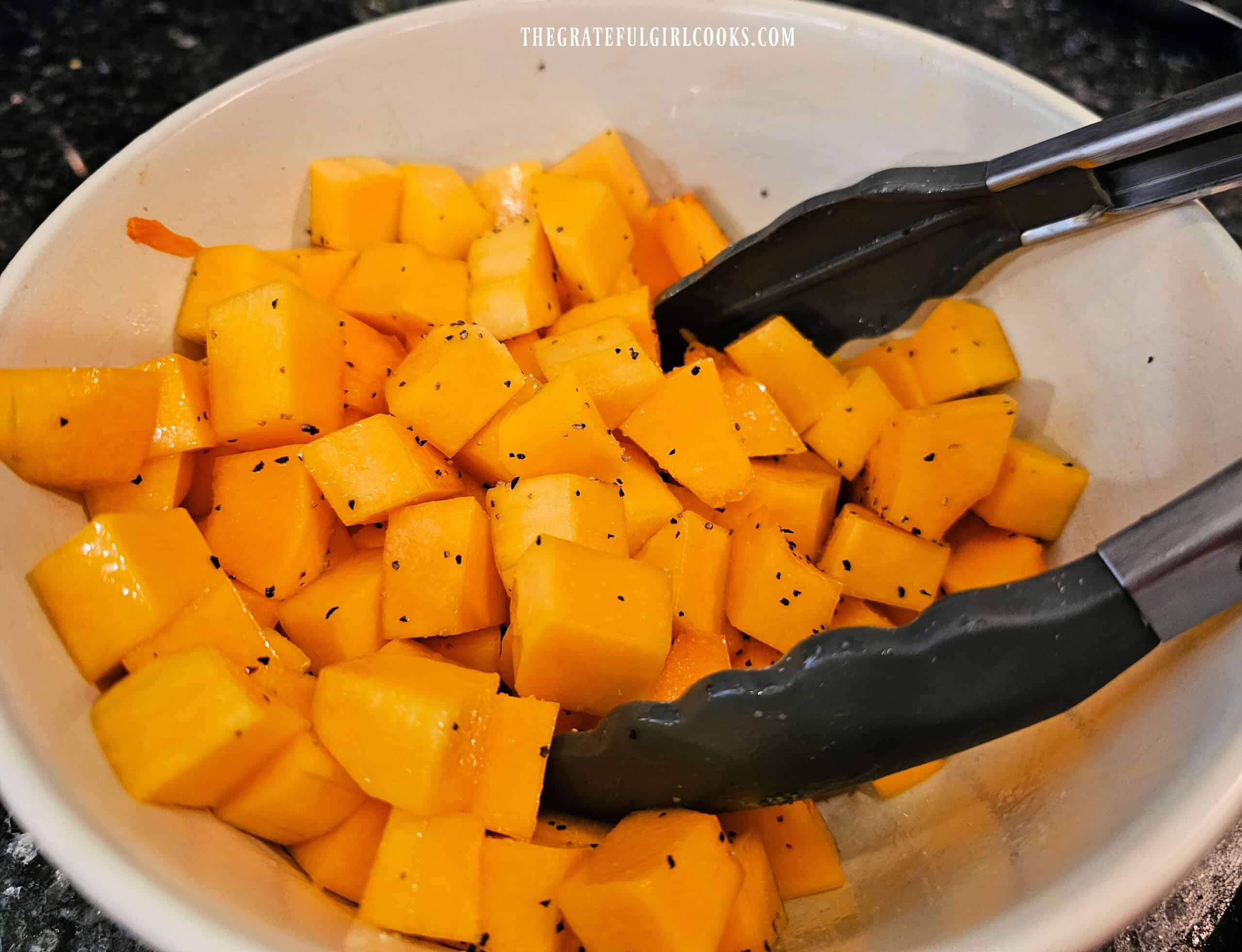 Squash cubes are tossed with olive oil, salt and pepper before roasting.