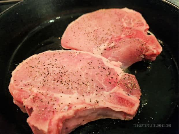 Seasoned pork chops are cooked in hot oil in a large skillet.