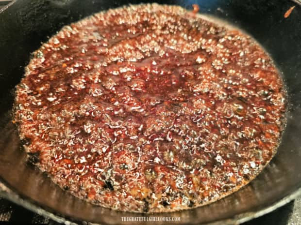 Raspberry balsamic sauce is cooked in skillet after cooked pork chops are removed.