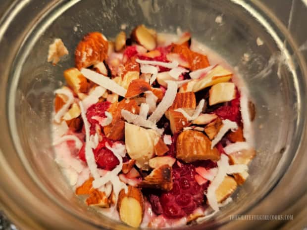 Raspberry Coconut Overnight Oats - The Grateful Girl Cooks! A jar of overnight oats is topped with almonds, coconut, and raspberries.